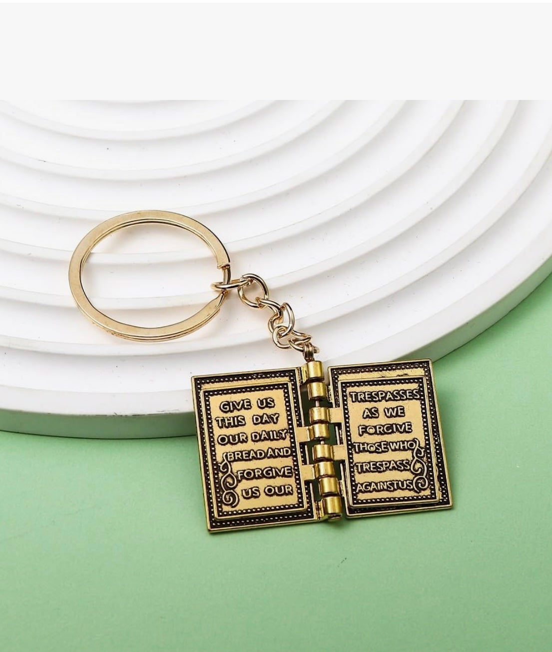 Keychain with open book design on a white and green background