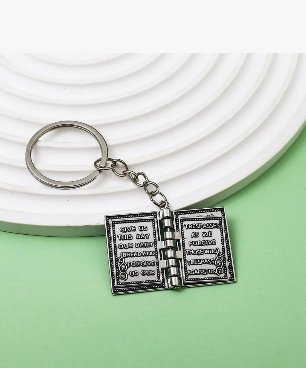 Keychain with open book design featuring text on a white and green background
