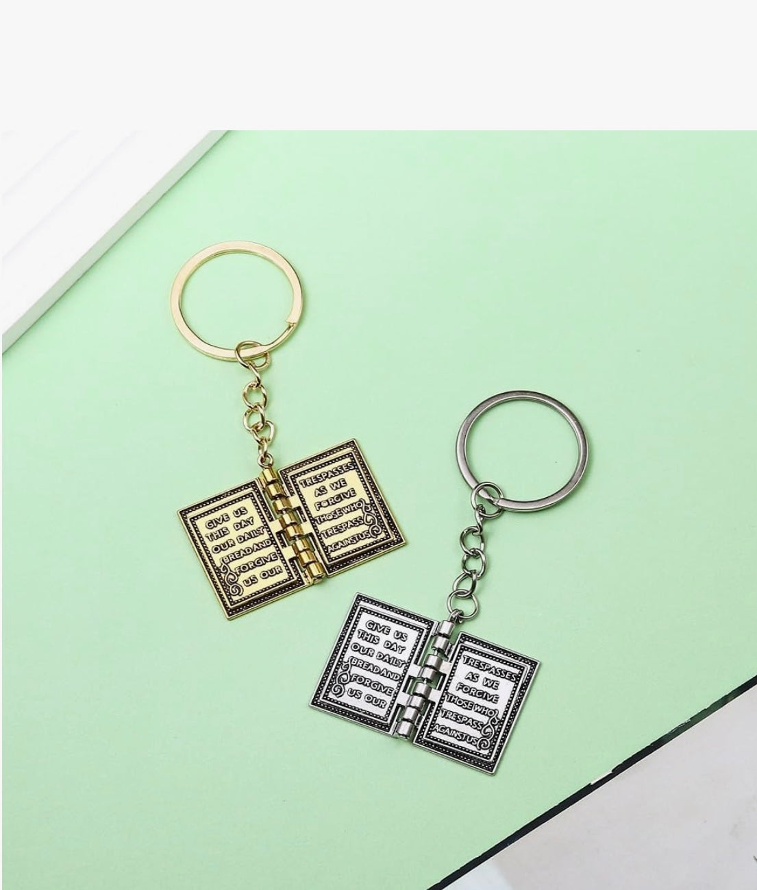 Two open book keychains on a light green background