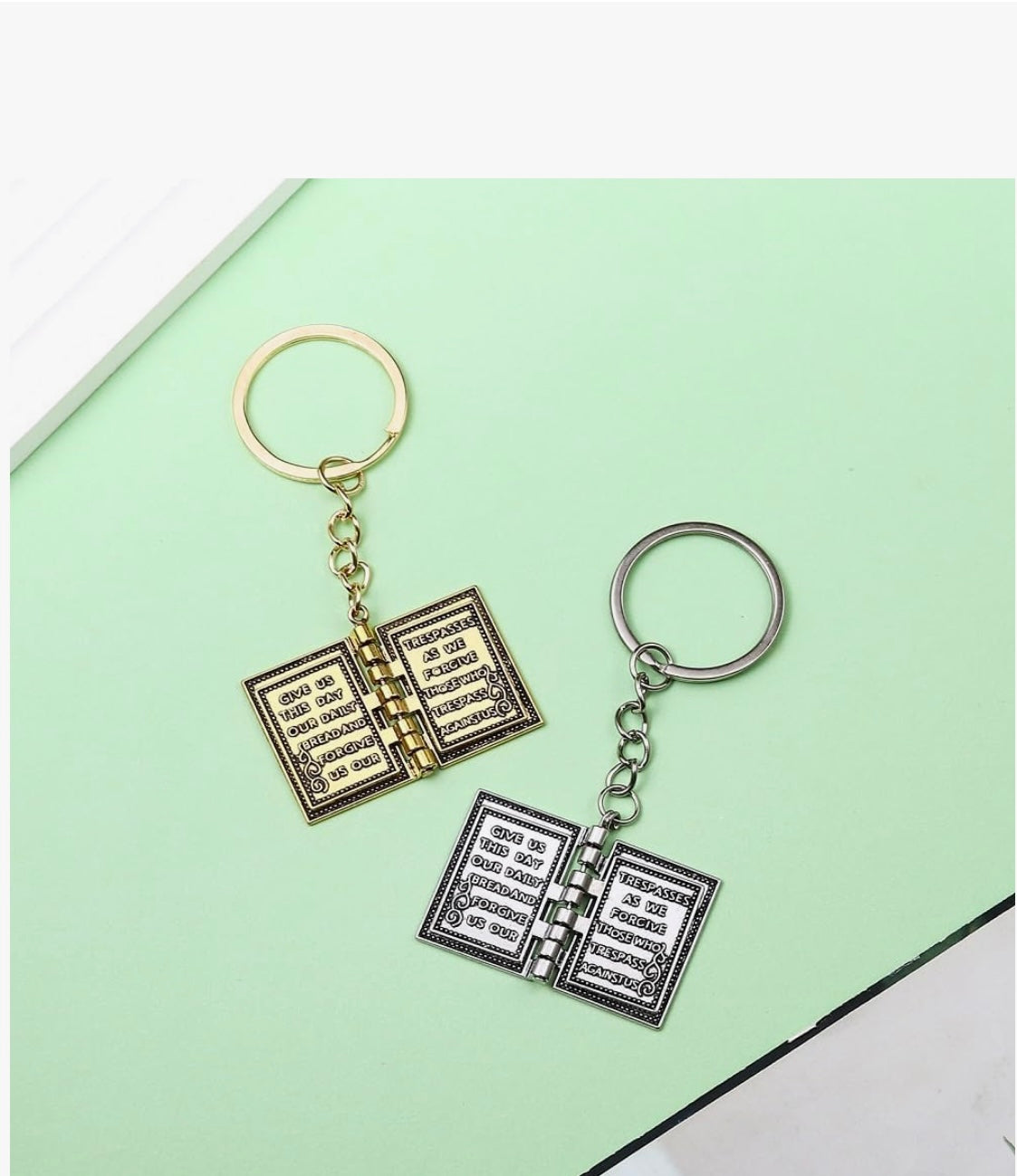 Two open book keychains on a light green background