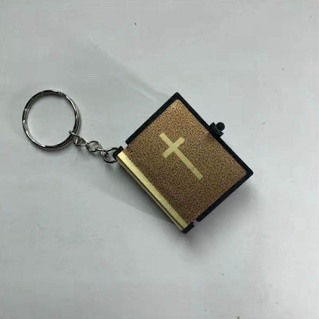 Three keychains shaped like miniature Bibles on a white background