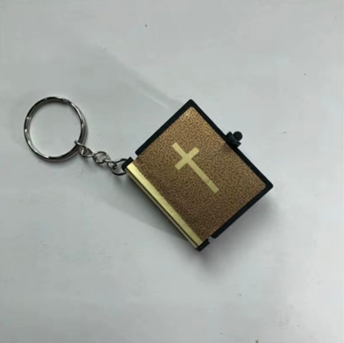 Keychain with a miniature book design featuring a cross on a white background