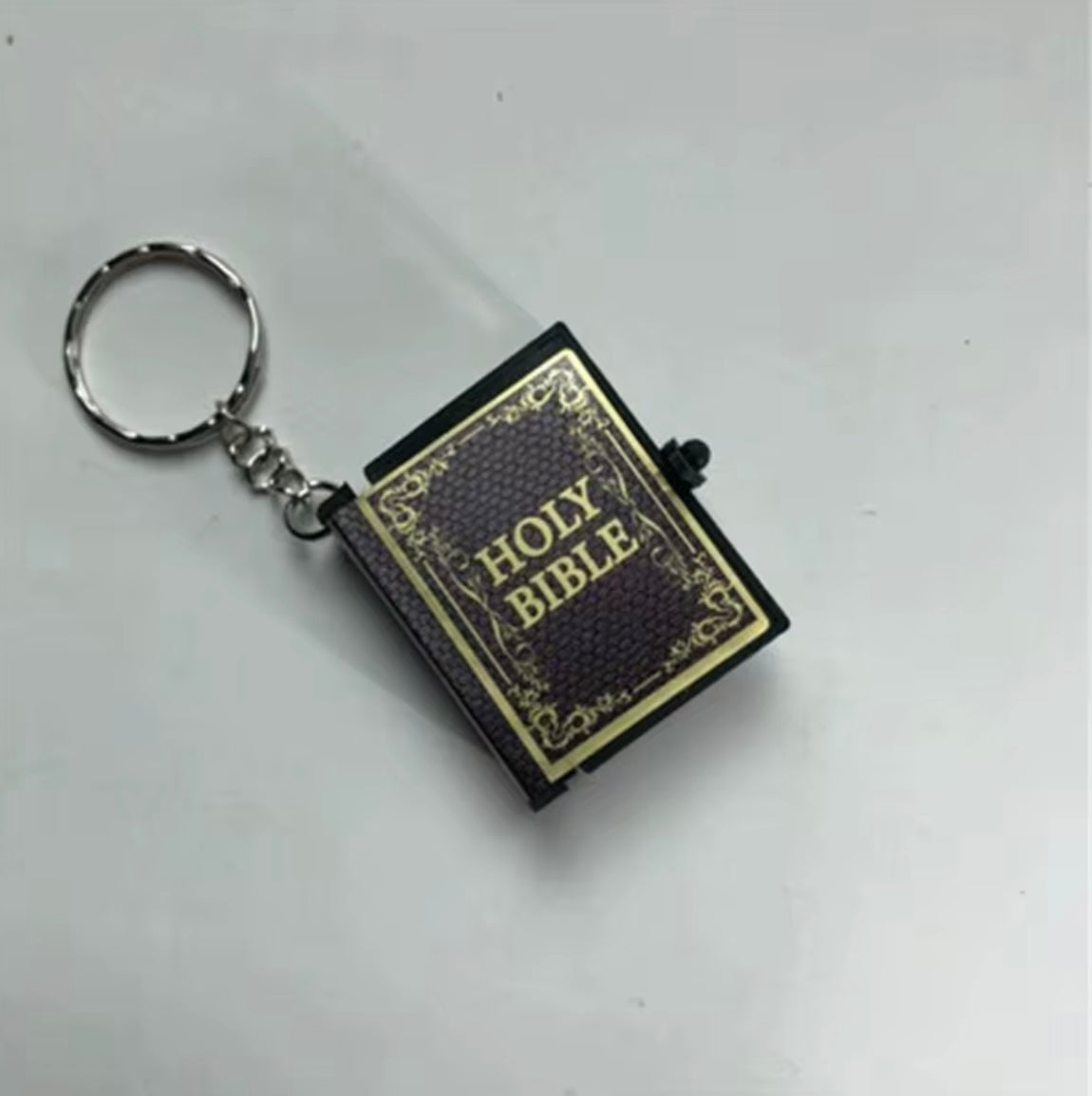 Keychain designed like a miniature Bible on a white background